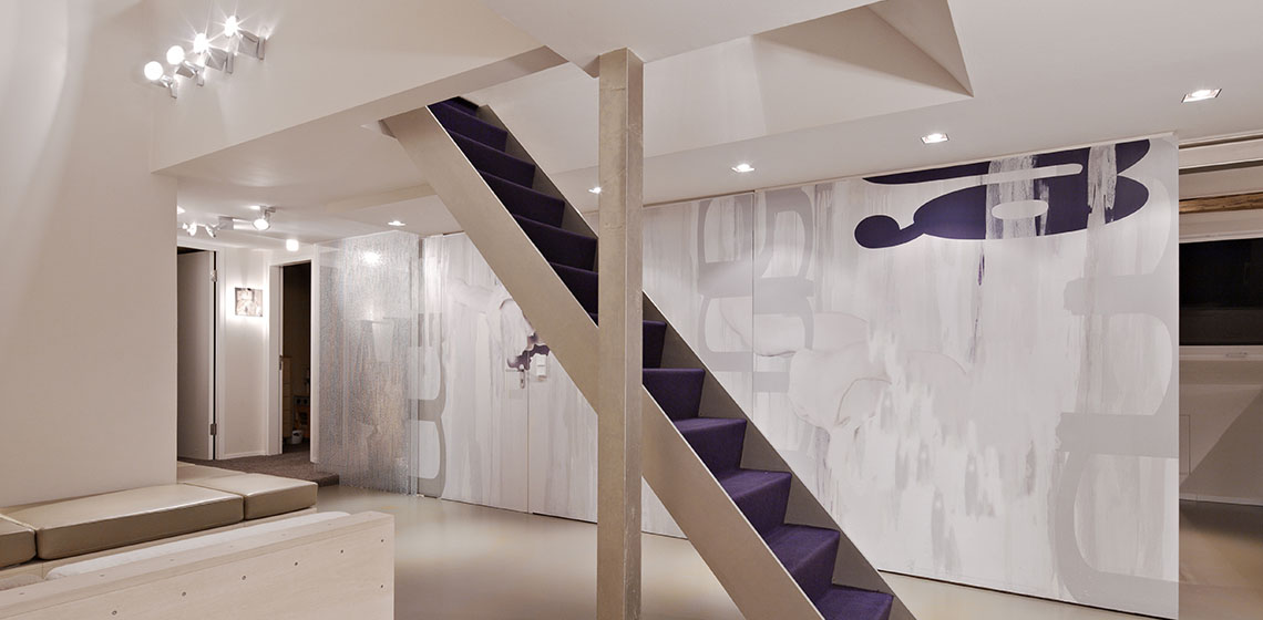 Modern interior featuring a stylish staircase with purple steps, minimalist decor, and abstract wall art in soft hues.
